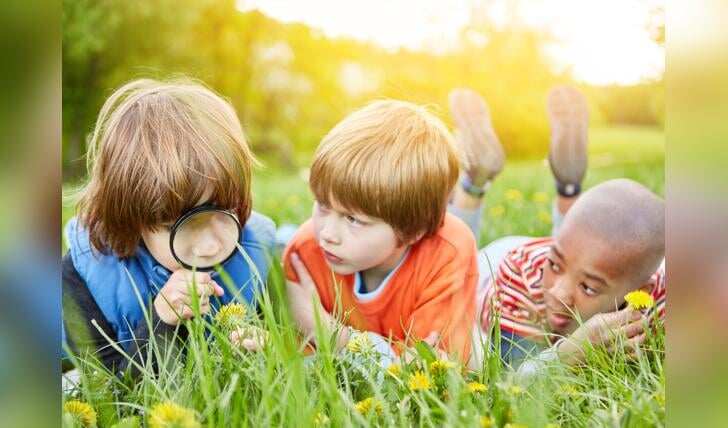 Kinderen in gras met vergrootglas