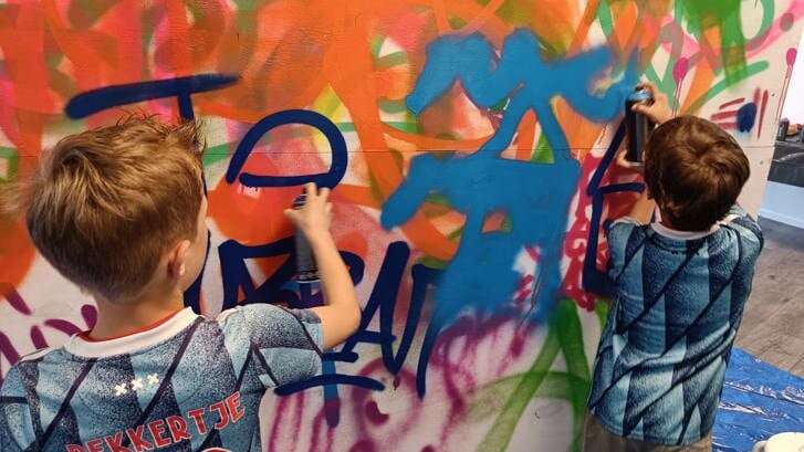 Kinderen leven zich uit met graffiti spuitbussen. Ze maken kleurrijke kunstwerkjes of laten hun naam achter.