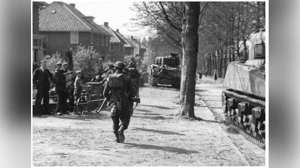 Britse infanterie en Canadese tanks op de Arnhemseweg in Ede. Burgers staan gewoon buiten om alles te zien ondanks de zeer gevaarlijke situatie.