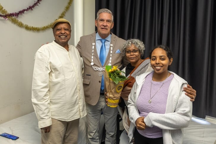 Burgemeester Naafs overhandigt een zonnebloem aan Soedanese familie.