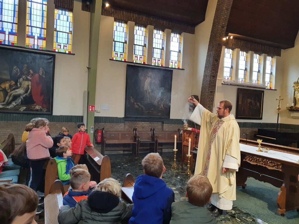 Pastoor Runhaar, die deze zomer naar Utrecht verhuist, laat een Amersfoortse schoolklas zien hoe in de kerk wierook wordt gebruikt.
