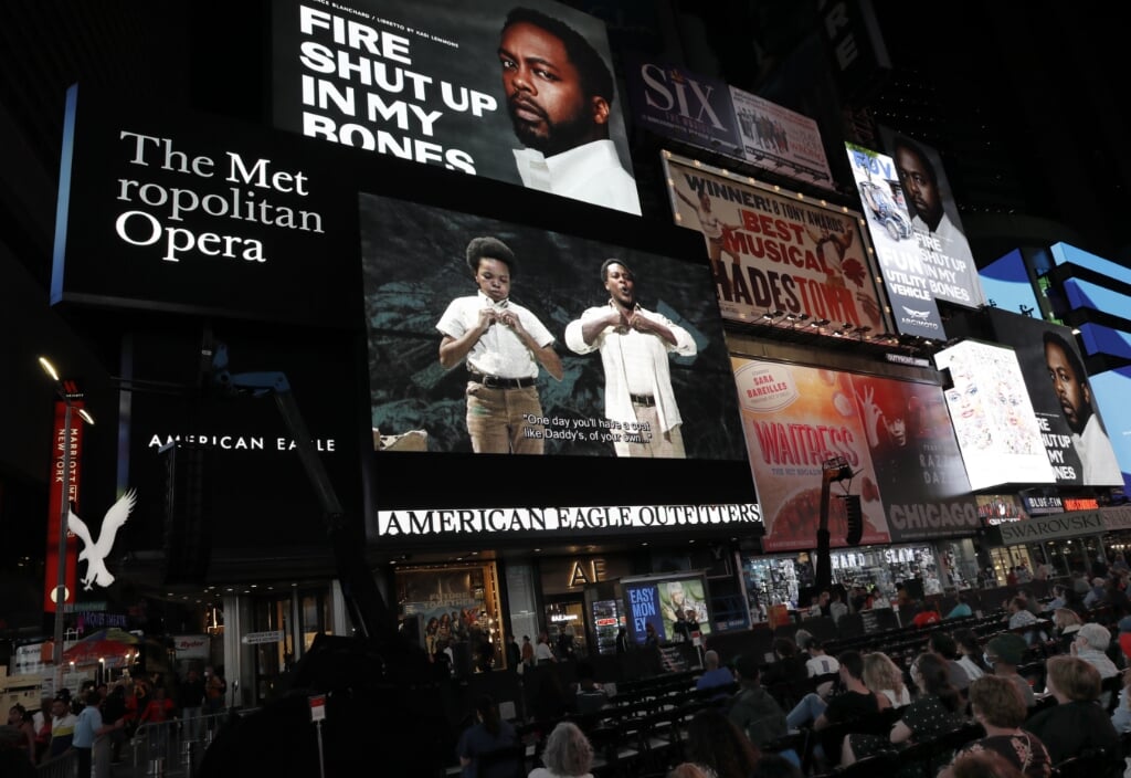 2021-09-27 07:23:21 epa09492224 Opera fans watch the opening night performance of 'Fire Shut Up In My Bones' streaming live from the Metropolitan Opera House, on jumbo screens in Times Square in New York, New York, USA, 27 September 2021.  EPA/Peter Foley