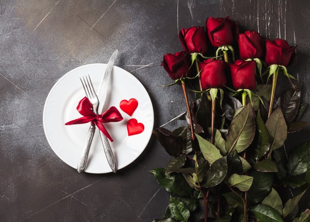Valentines day table setting romantic dinner marry me wedding engagement with red rose gift and plate fork knife on dark background with copyspace. Love flower gift woman making proposal