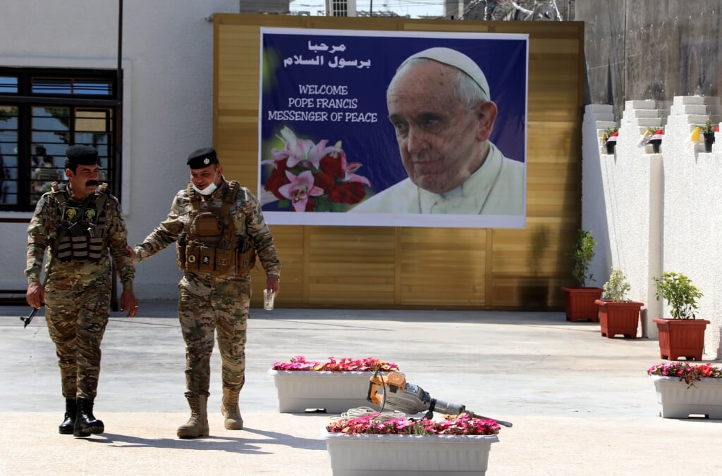 2021-03-01 10:23:23 epa09044899 Iraqi policemen walk next to a posters depicting the picture of Pope Francis at the St. Joseph Chaldean Catholic Church in Baghdad's Karada district, Iraq on 01 March 2021. Pope Francis will visit St. Joseph church in Baghdad, during his trip to Iraq from 05 to 08 March 2021.  EPA/AHMED JALIL