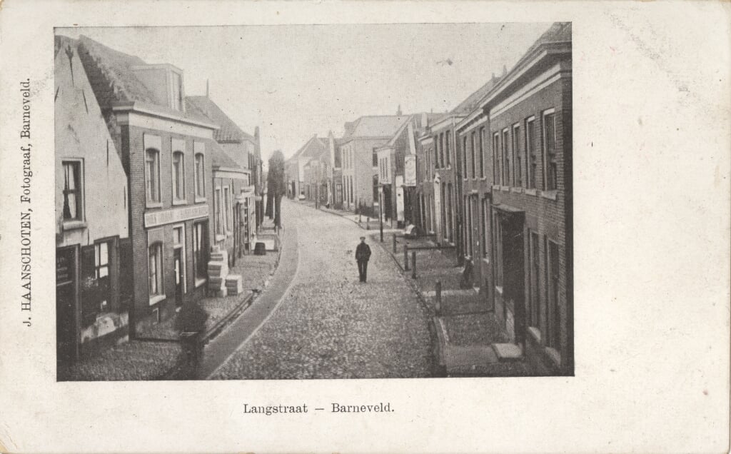 Jacob Haanschoten hing ver uit zijn bovenraam om deze foto van de Langstraat met het pand van Boonstra te kunnen maken. Op de stoep pakken met drukwerk .