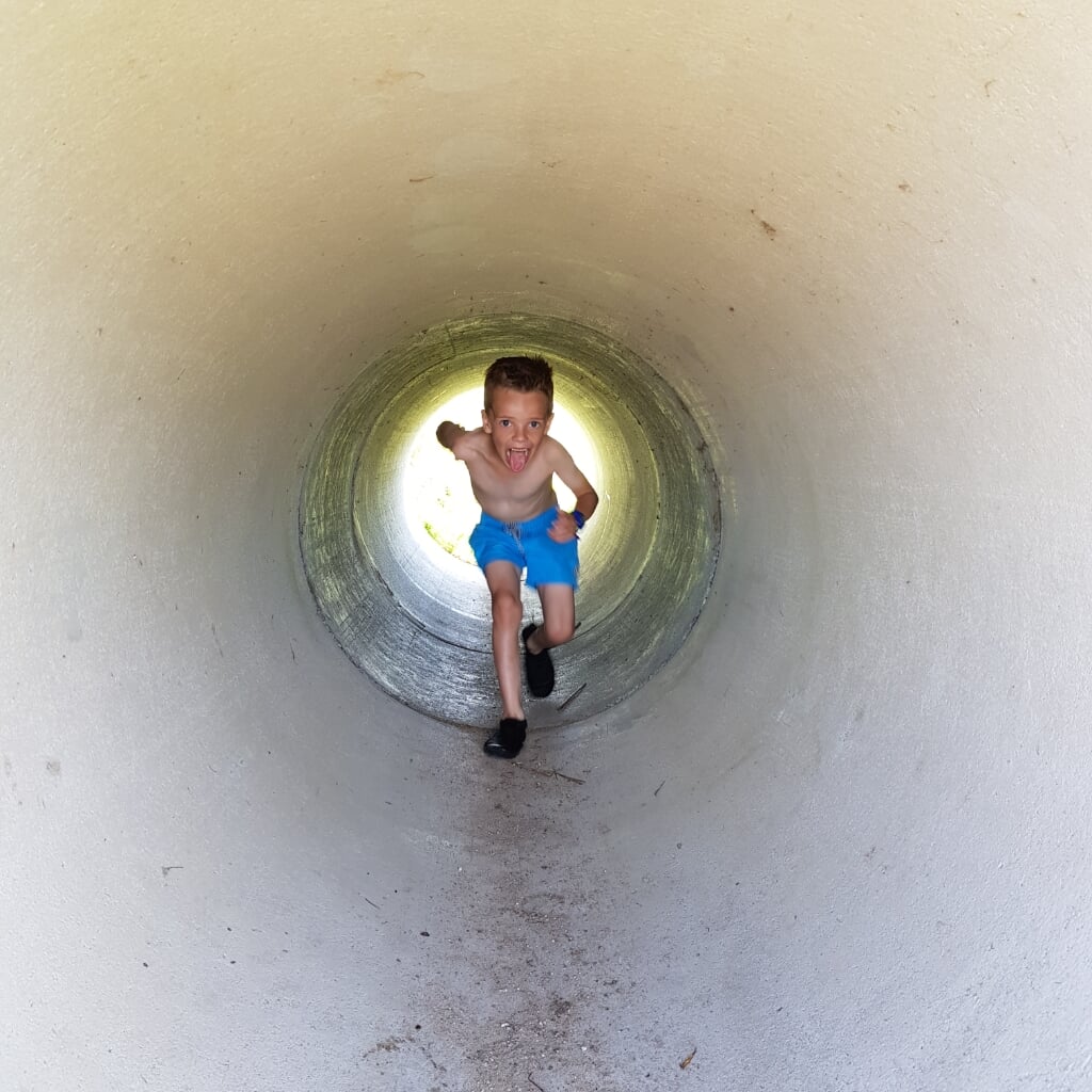 Onze zoon Ezra (6 jaar) op volle snelheid door een buis bij natuurspeelplaats Atlantia in Middelharnis.