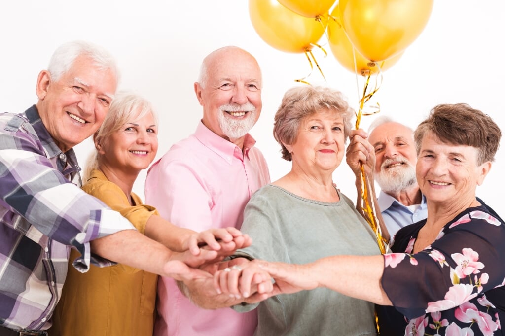 Happy old people having fun in white room holding balloons