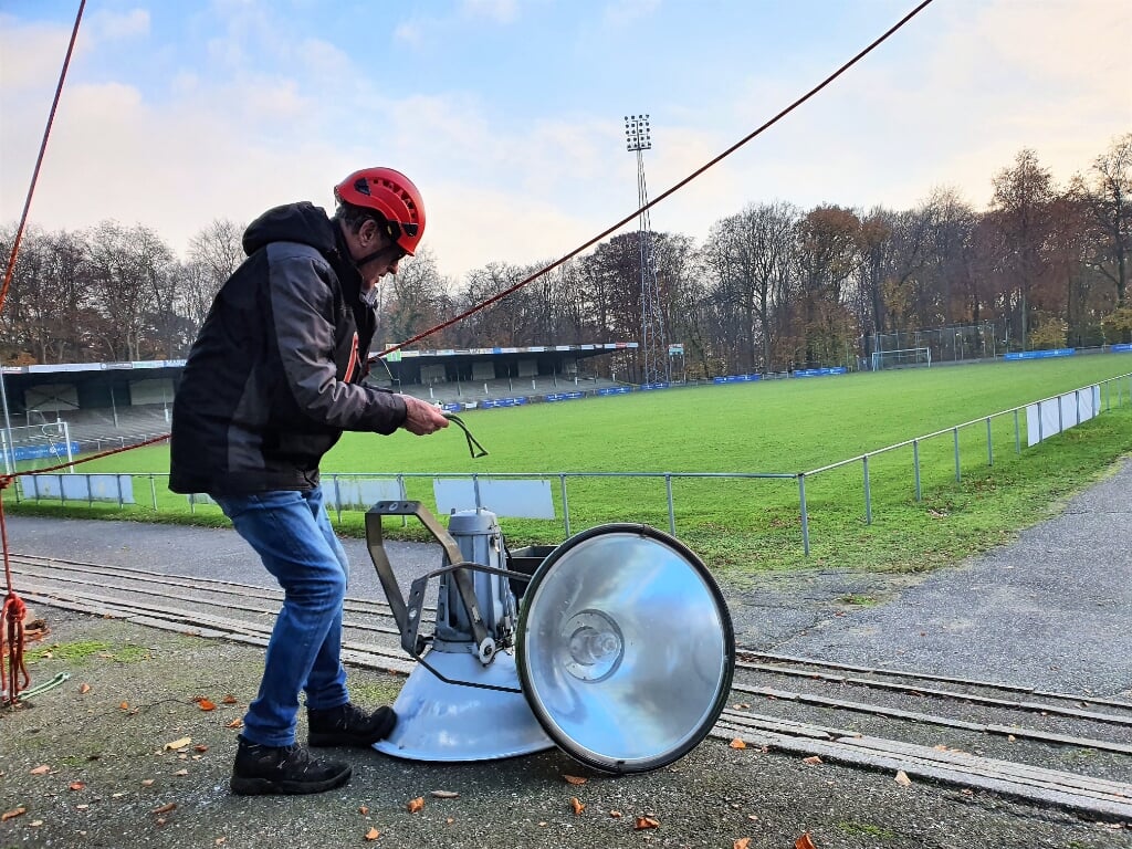 Stadioncoördinator Herman Suijdendorp met een tweetal lampen die vanuit een lichtmast naar beneden zijn komen 'abseilen'. 