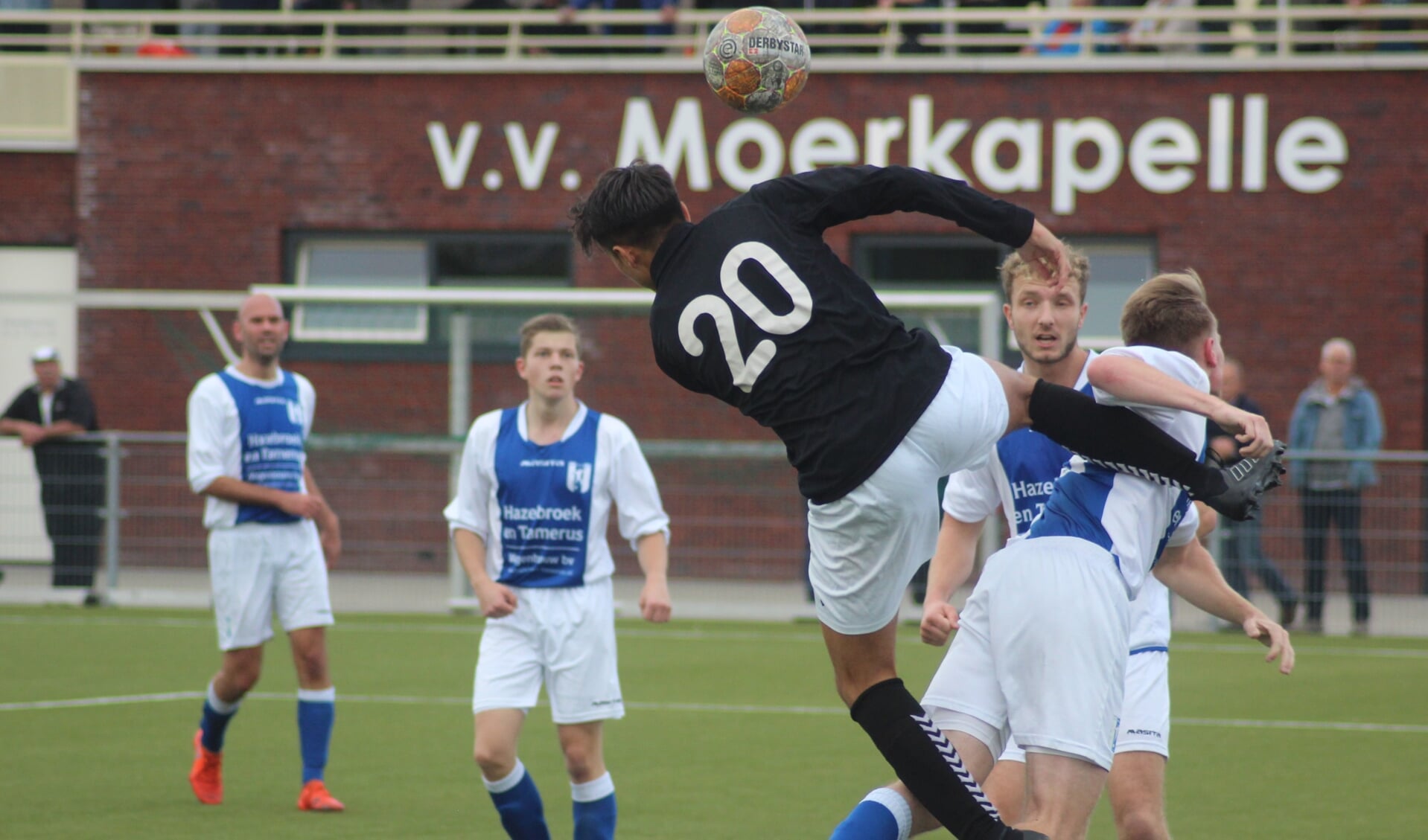 Davey Hehakaja springt Moerkapelle-verdediger Thijs van Nieuwkoop in de rug.