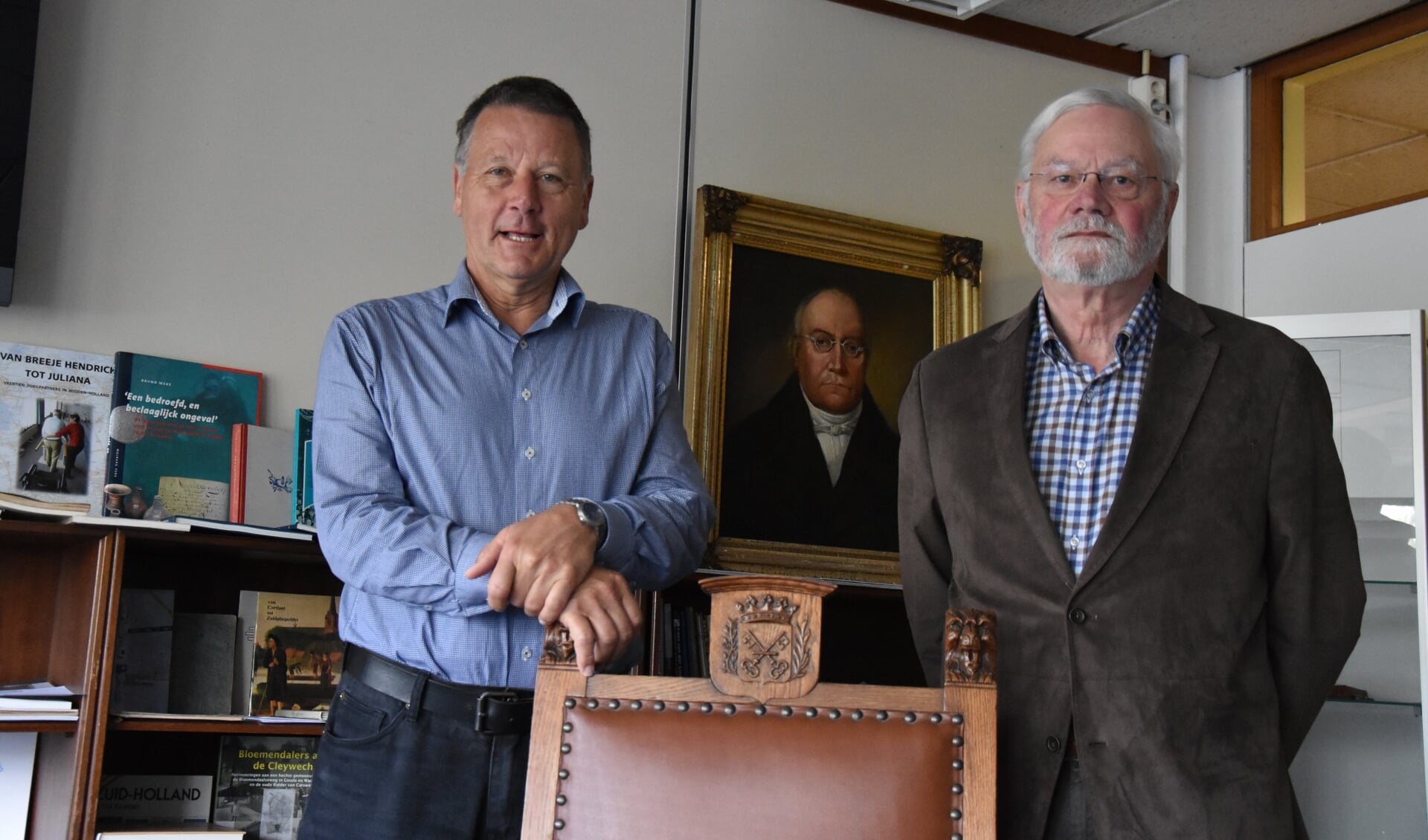 Henk Revoort en Leen de Jong bij de oude burgemeestersstoel.