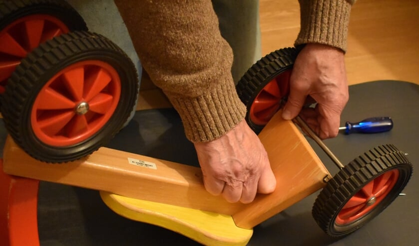 Een vastgelopen wieltje repareren of een paar schroefjes aandraaien; een houten fietsje wordt bij het Repair Café zo opgelapt.