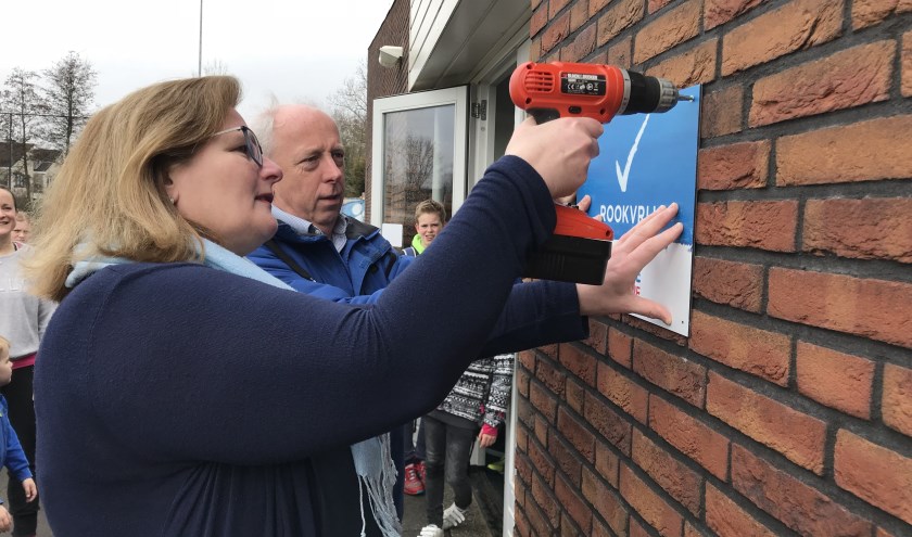 Toenmalig wethouder Brigitte Leferink schroefde in maart 2018 het rookvrij-bordje op de muur bij HCW. (foto: archief HvH)