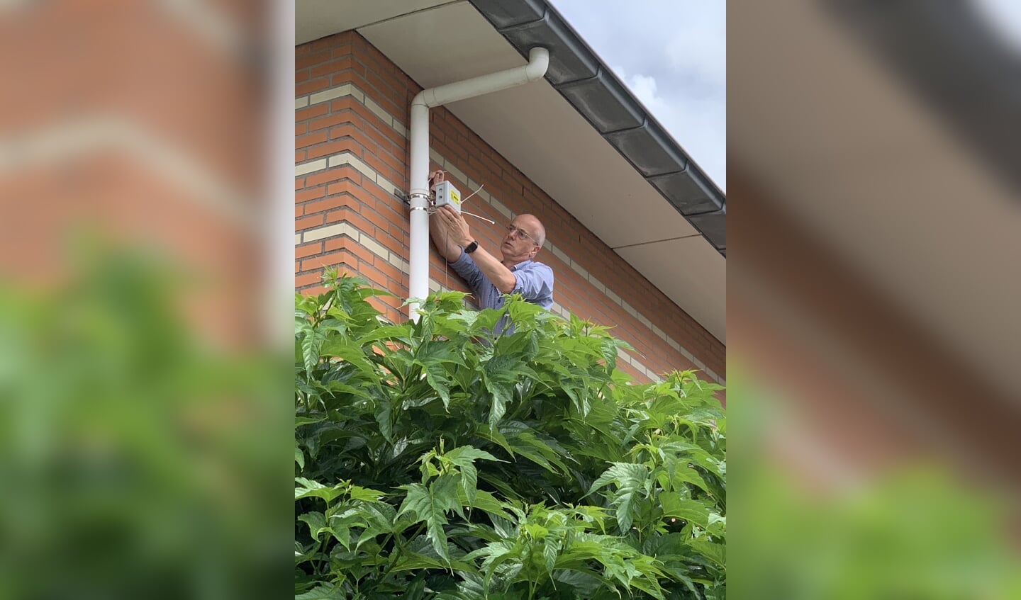 De fijnstofmeter wordt geïnstalleerd aan de gevel van een huis.