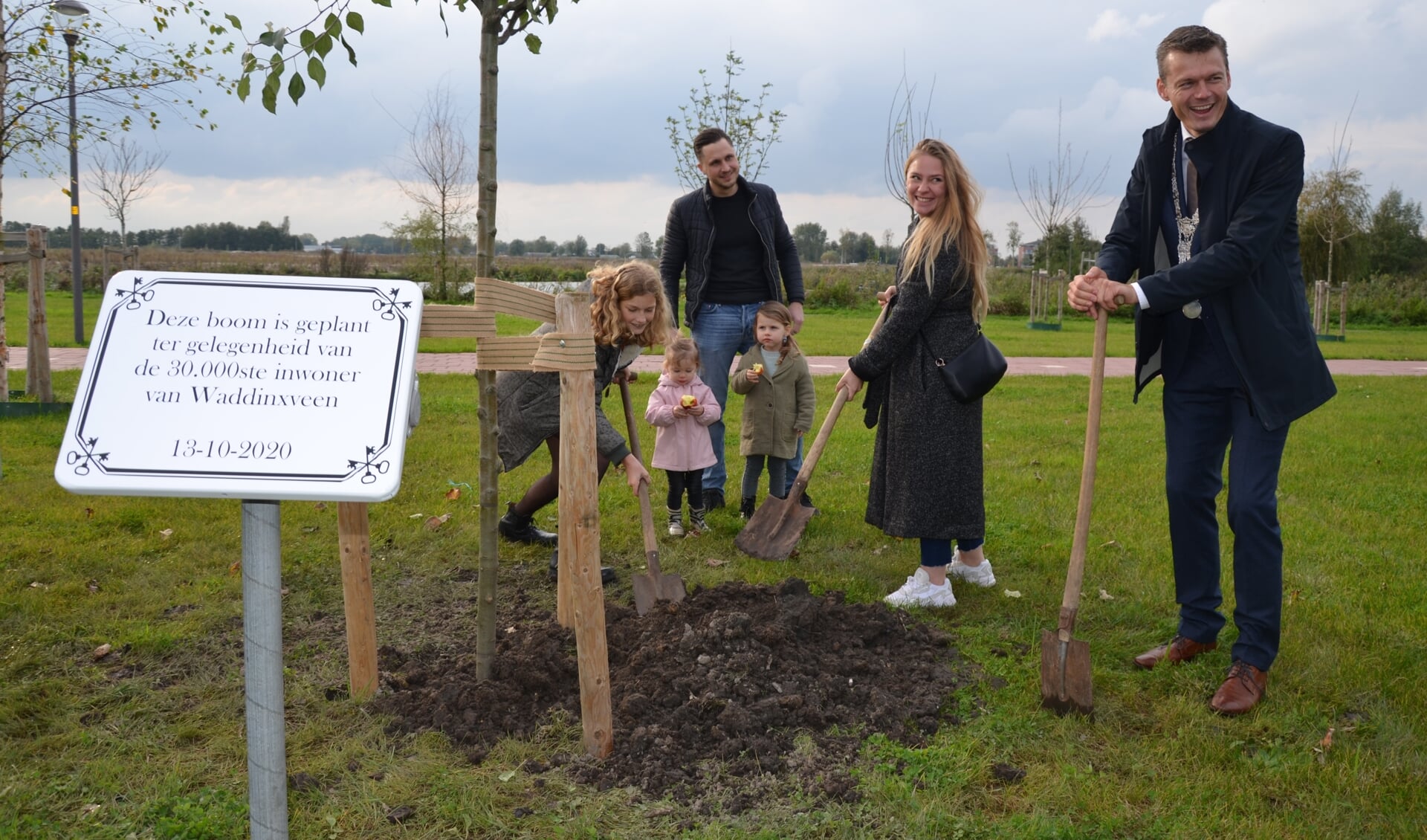 Burgemeester Nieuwenhuis en de familie Kraaijeveld worden bij het planten geholpen door kinderburgemeester Liva.