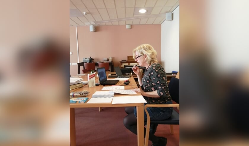 Een van de activiteitenbegeleiders leest een bingoverhaal voor aan de bewoners op hun kamers.
