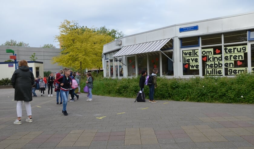 Kleine groepjes leerlingen worden op het schoolplein van de Kardinaal Alfrinkschool opgewacht door de eigen leerkracht.