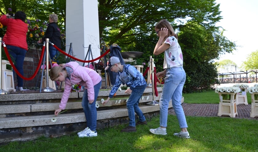 Fiene (links), Jimme en Silke Wijnstra legden een bloem bij het oorlogsmonument in Waddinxveen.