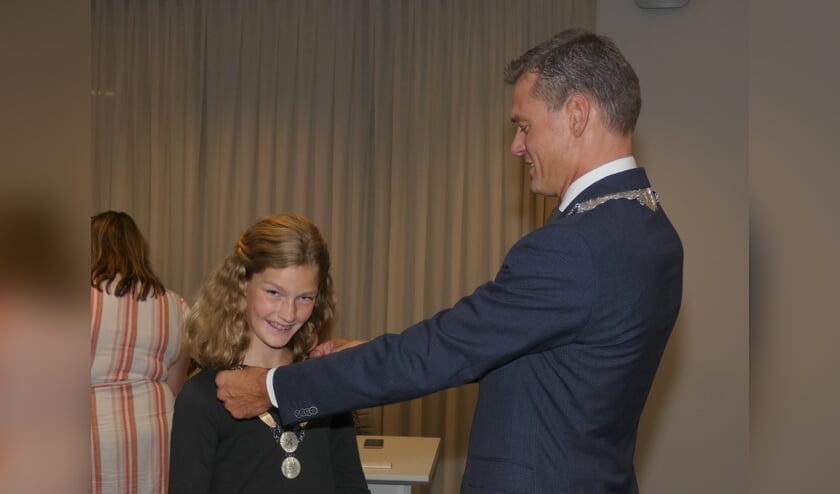 <p>Trots kijkt de eerste kinderburgemeester van Waddinxveen in de camera toen zij haar ambtsketen kreeg omgehangen door burgemeester Nieuwenhuis.</p>