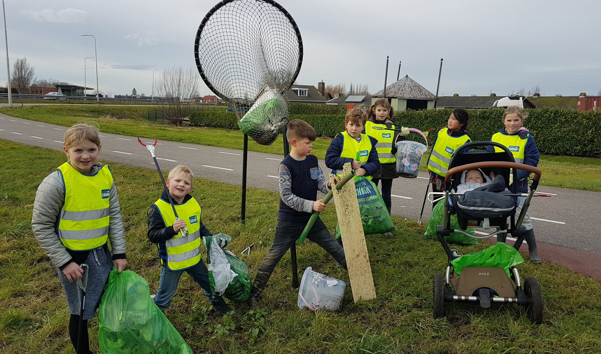 Kinderen uit de buurt van de Henegouwerweg worden door Willem van Dorp aan 'het werk' gezet met prikkers en afvalzakken.