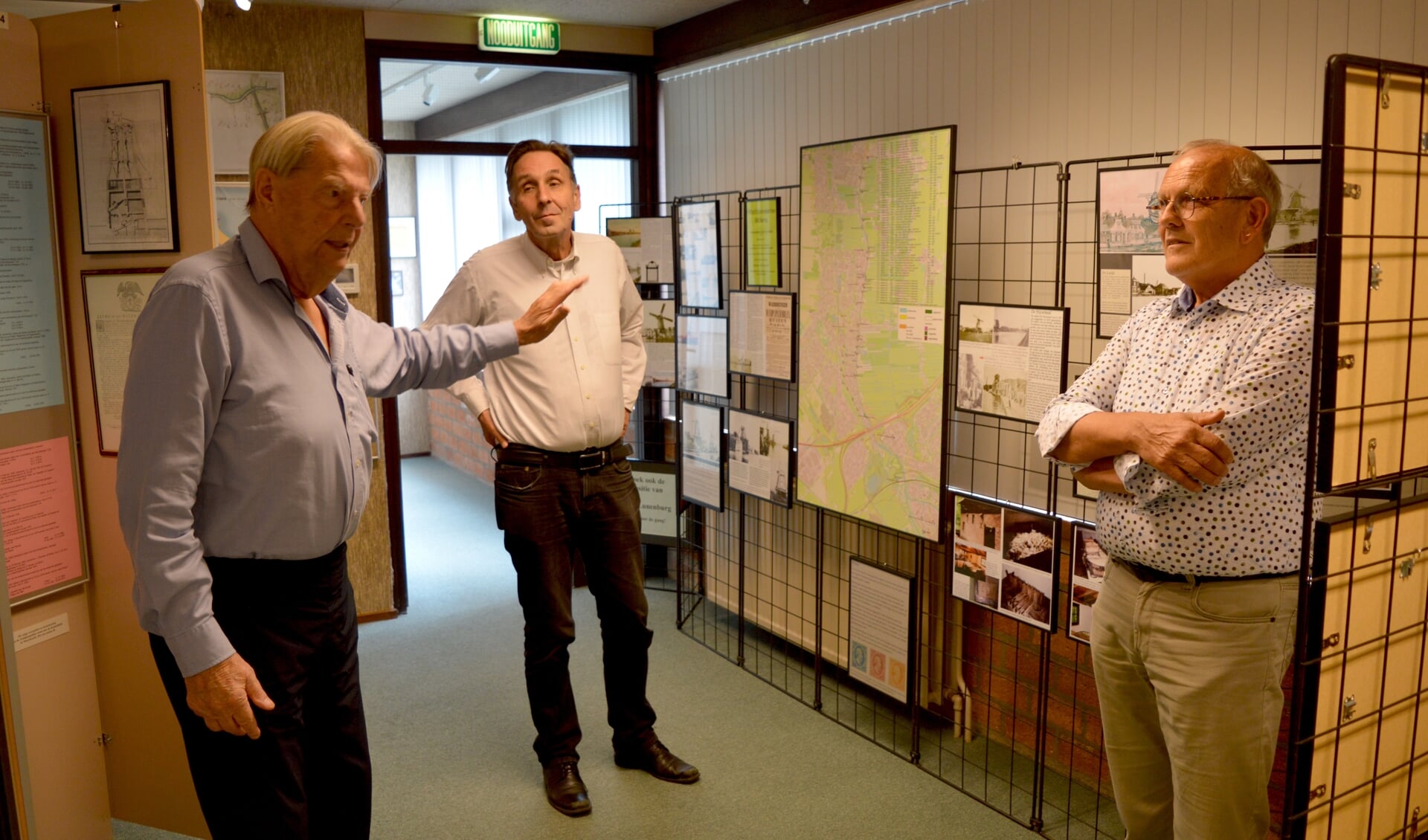 Dekker (links) geeft uitleg bij zijn Waddinxveense molententoonstelling; Van der Zalm en Ottevanger luisteren.