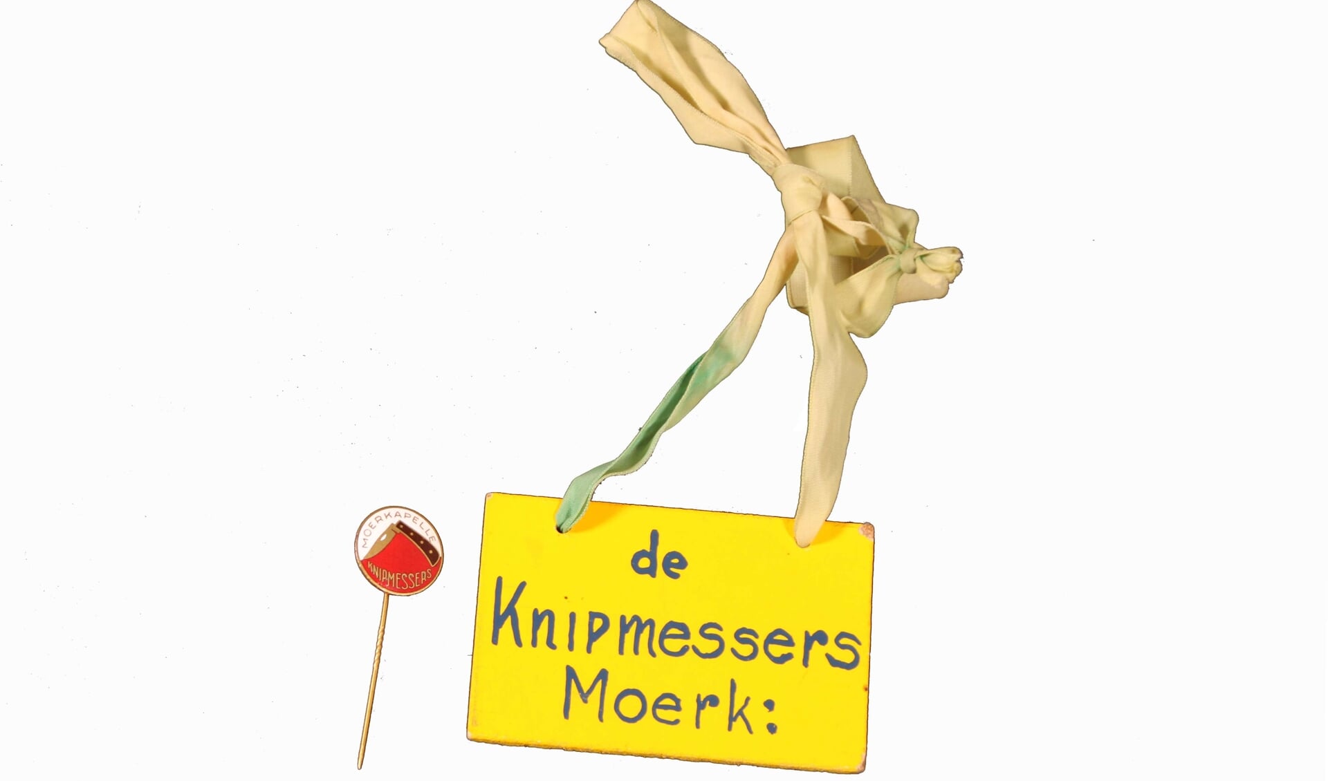 Een speldje en een naamkaartje van de Moerkapelse carnavalsvereniging ‘de Knipmessers’.