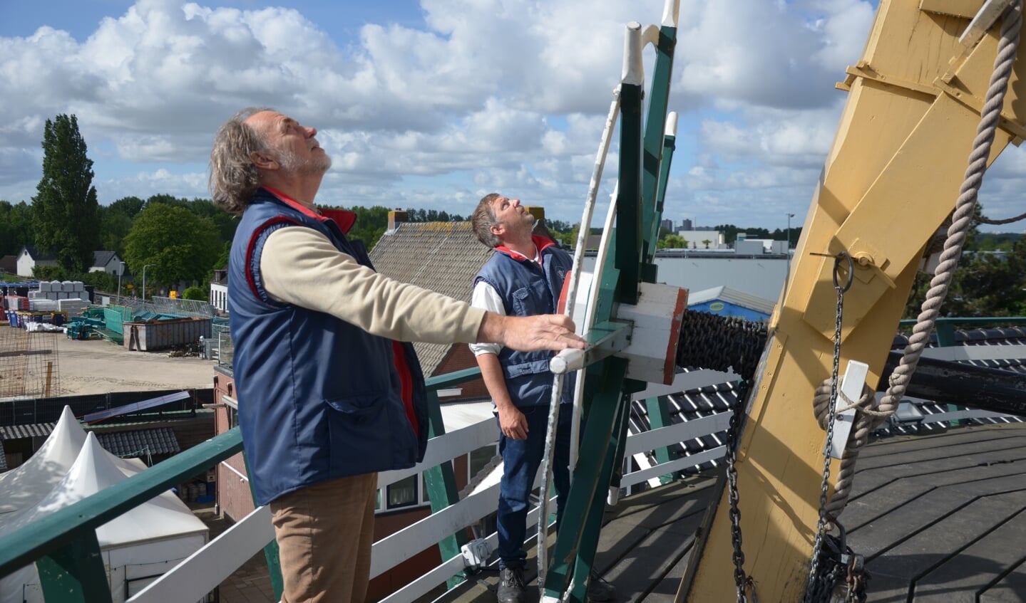 Bovenop de molen waait een vaandel waaraan te zien is of het groen-witte kruiwiel op de goede plek staat.