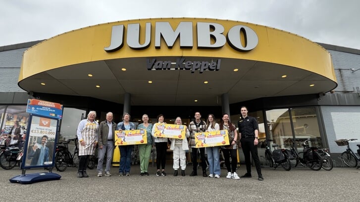 Trimsportvereniging Be Fit, EHBO Zevenhuizen en Gymnastiekvereniging O.S.S. poseren met hun cheque voor de ingang van Jumbo.