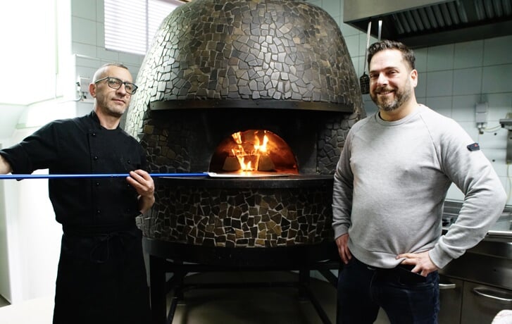 Chef-kok Lucio en eigenaar Marco bij de met hout gestookte oven. 