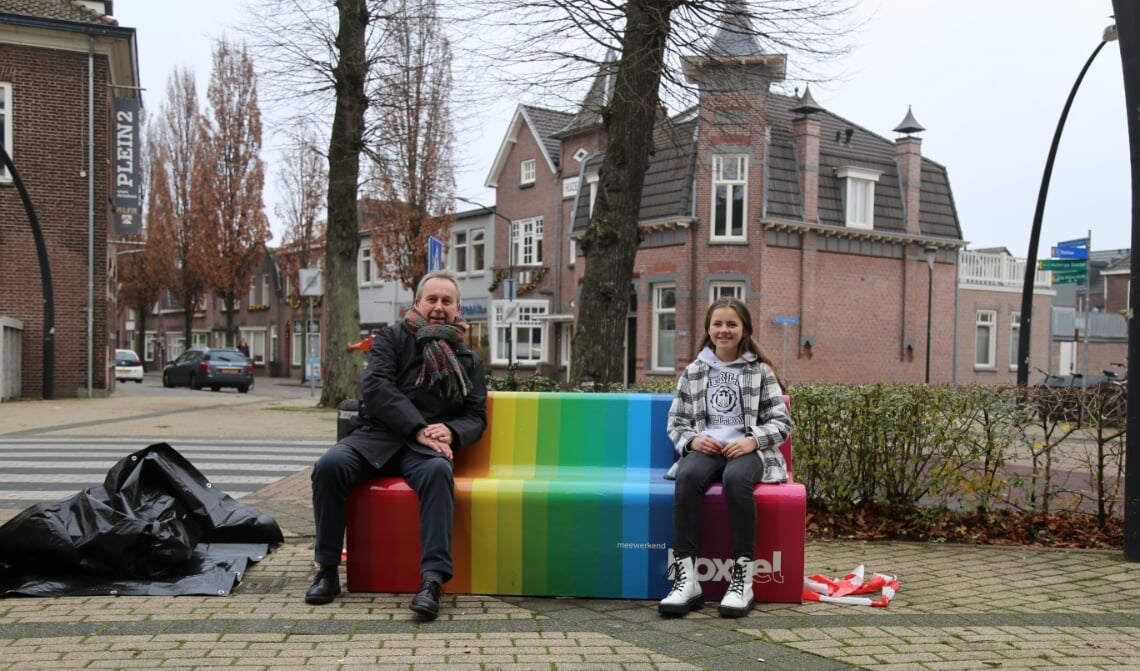 Wethouder Herman van Wanrooij en Tess Scheepers, zittend op het nieuwe regenboogbankje.