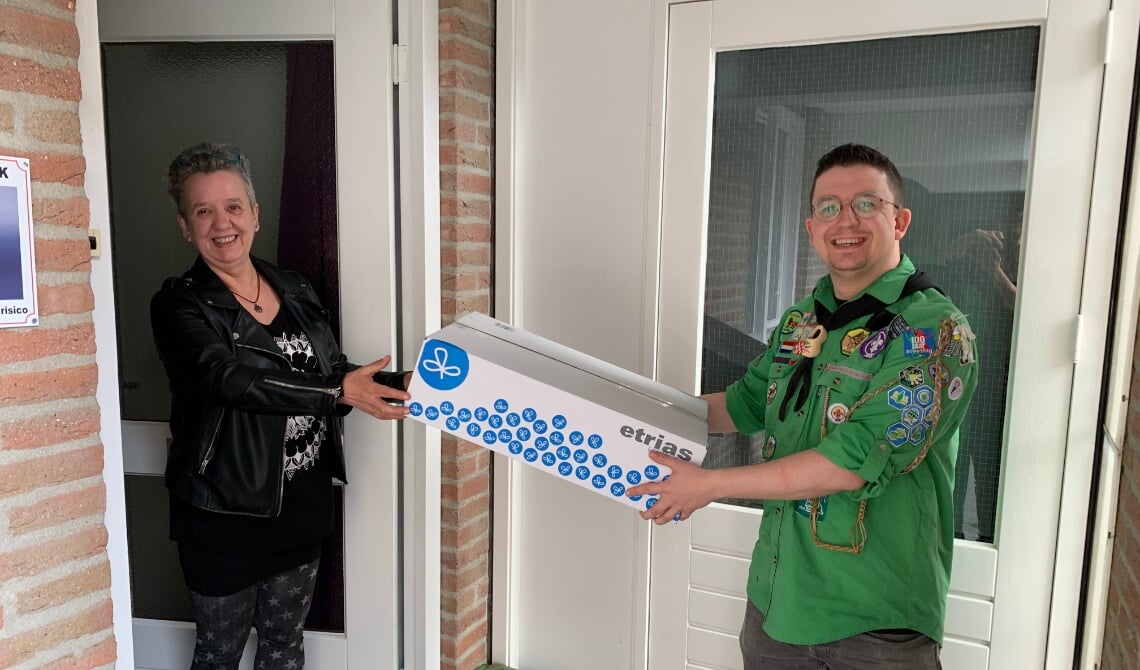 <p>Een moeder neemt de box in ontvangst, uit handen van de leiding. (Foto: Scouting Boxtel)</p>