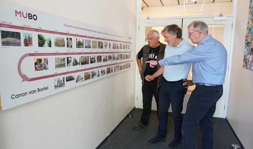Leerkracht Gerrit de Jong (l.) en directeur van de Angelaschool Jos Korsten (m.) bekijken samen met MUBO-voorzitter Willem van Vossen de canon van Boxtel.