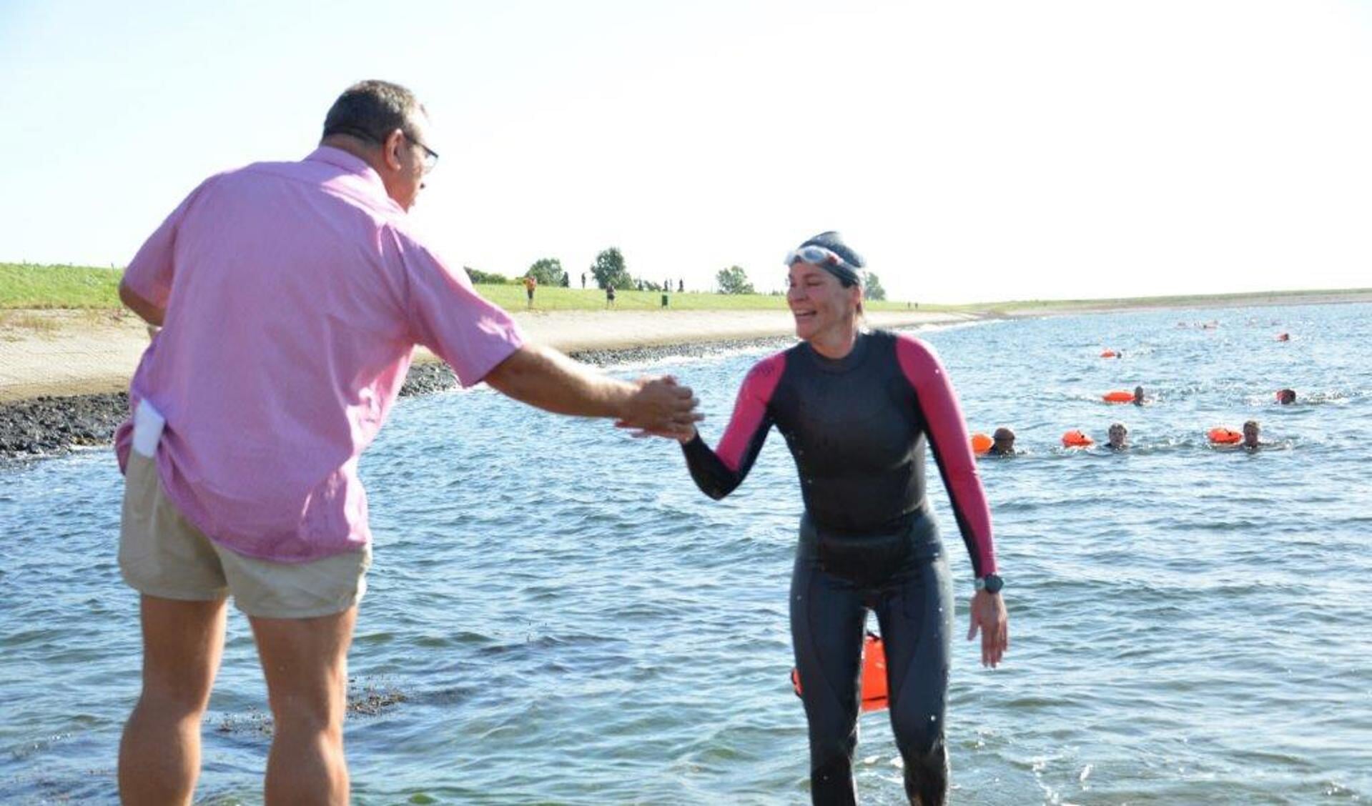 Organisator Andy van de Velde verwelkomt een zwemster in het haventje van Strijenham. 