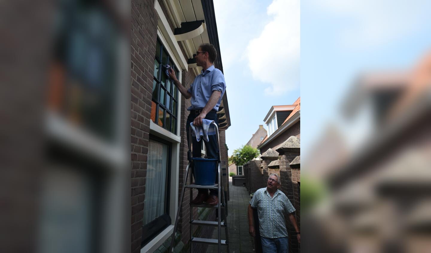 Wethouder Peter Hoek helpt mee bij de Hervormde Kerk in Stavenisse. Rechts Henk Westerlaken. 