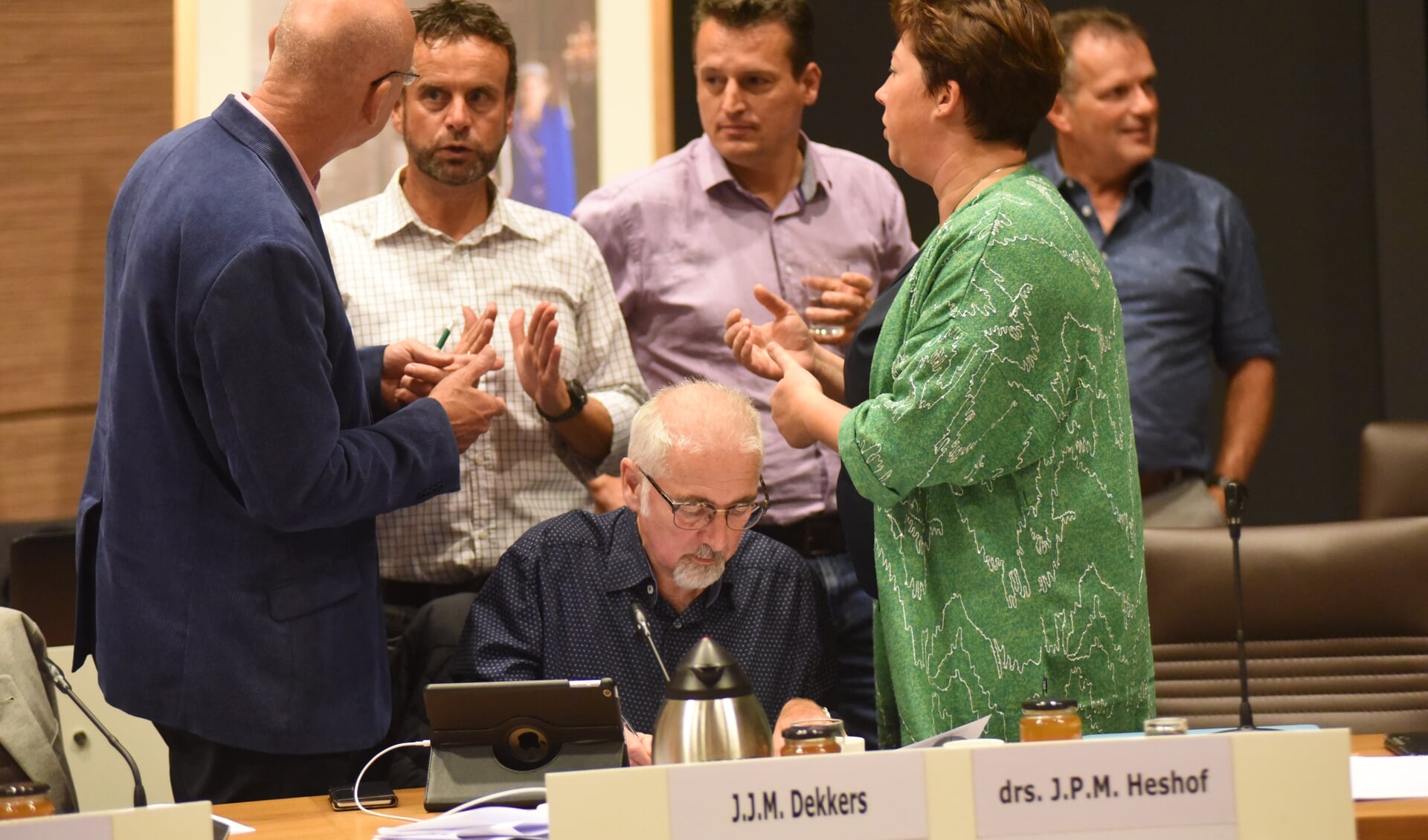 Beeld uit de bewuste raadsvergadering. Raadsleden van CDA, VVD en Pvda/GL in gesprek over de motie over de regenboogvlag. Jacques Dekkers (zittend) diende die in. 