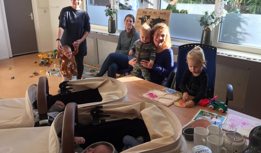 Dorien Lomeijer (midden achter) ziet hoe haar dochter Evi speelt aan de tafel waarop de maxi-cosi’s met haar broertje Joey en zusje Lisa – een tweeling – staan. Links Sharita van der Meulen met dochter Eora en rechts Marieke Heinsbroek met zoontje Kees op schoot.