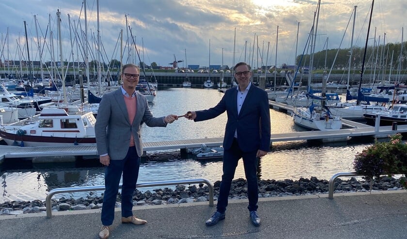 <p>Marton Overbeeke (links) neemt het stokje over van Harm-Jan van Dijke. Ze staan op de foto in de jachthaven van Sint-Annaland.</p>