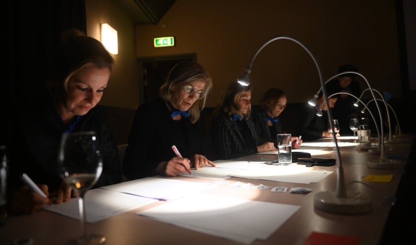 De jury, echtgenotes van Lions-leden, kijken de antwoordformulieren aan.