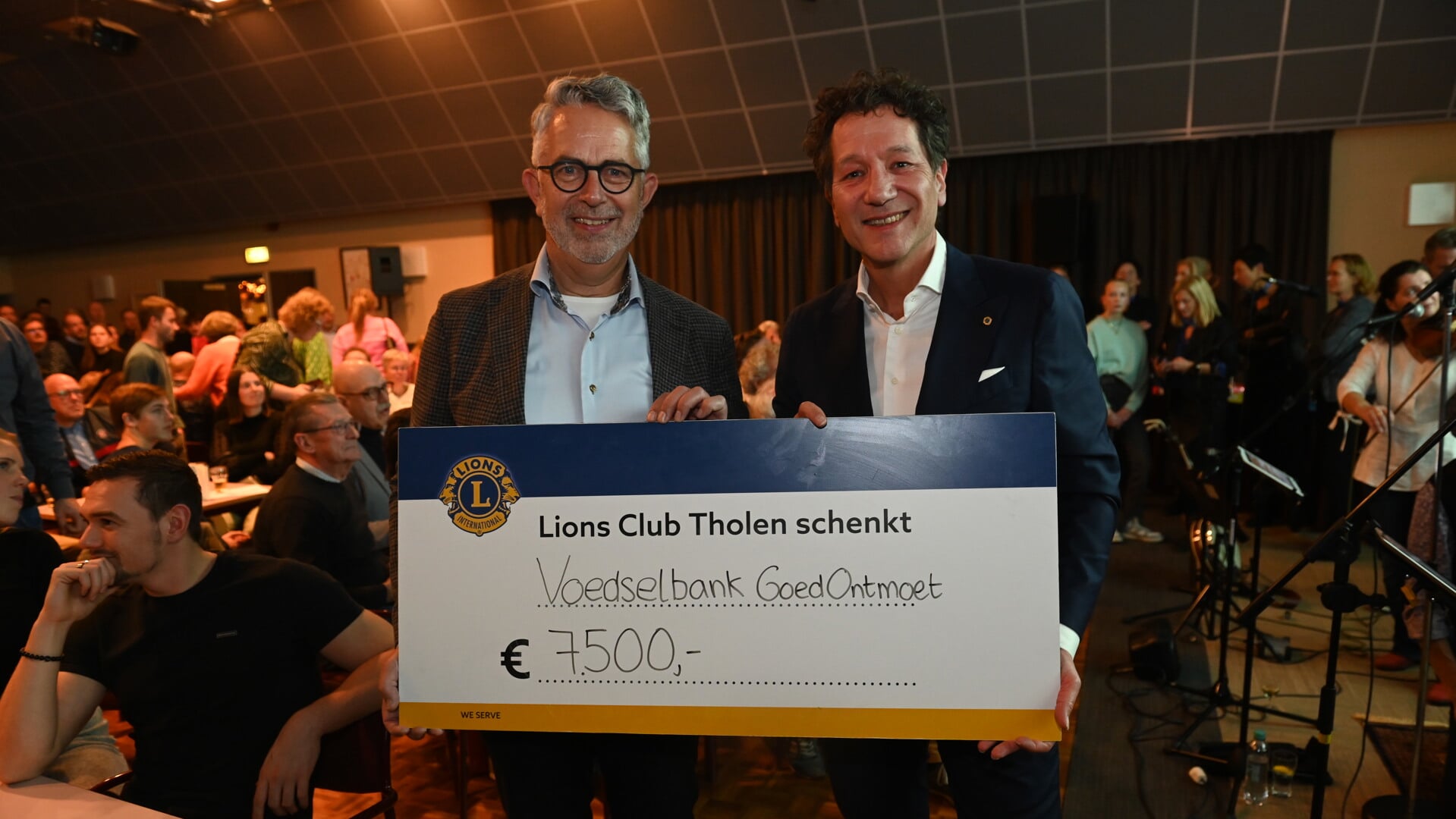 Quizmaster Wim van de Ree en president Ad Duvekot met de cheque. 