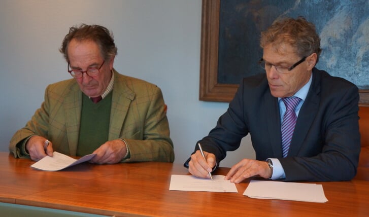 Pieter van de Kamp (l) en Ad van der Heijden ondertekenen het convenant