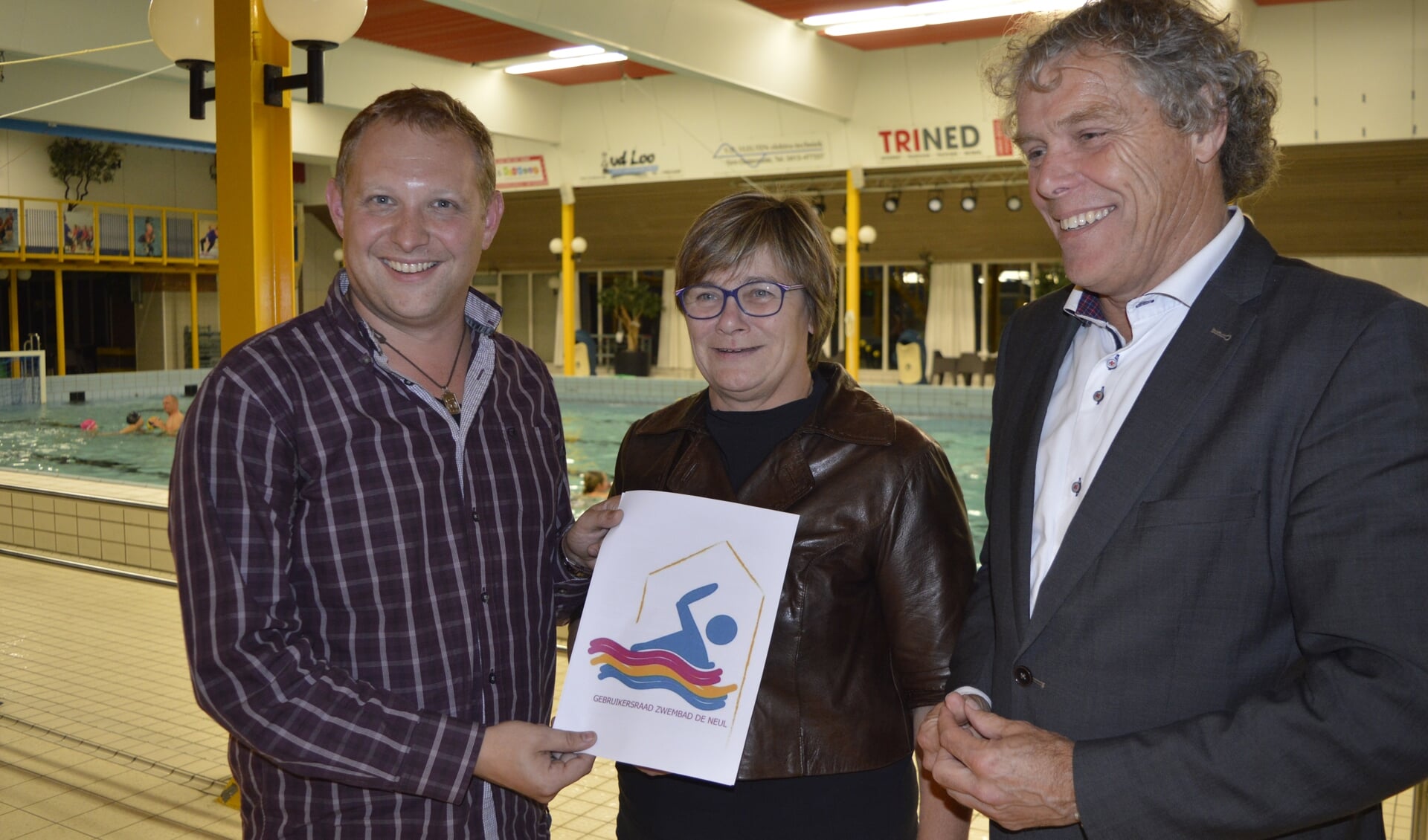 Tom van Wanrooij overhandigt het logo aan wethouders Hendriks en Van der Heijden 