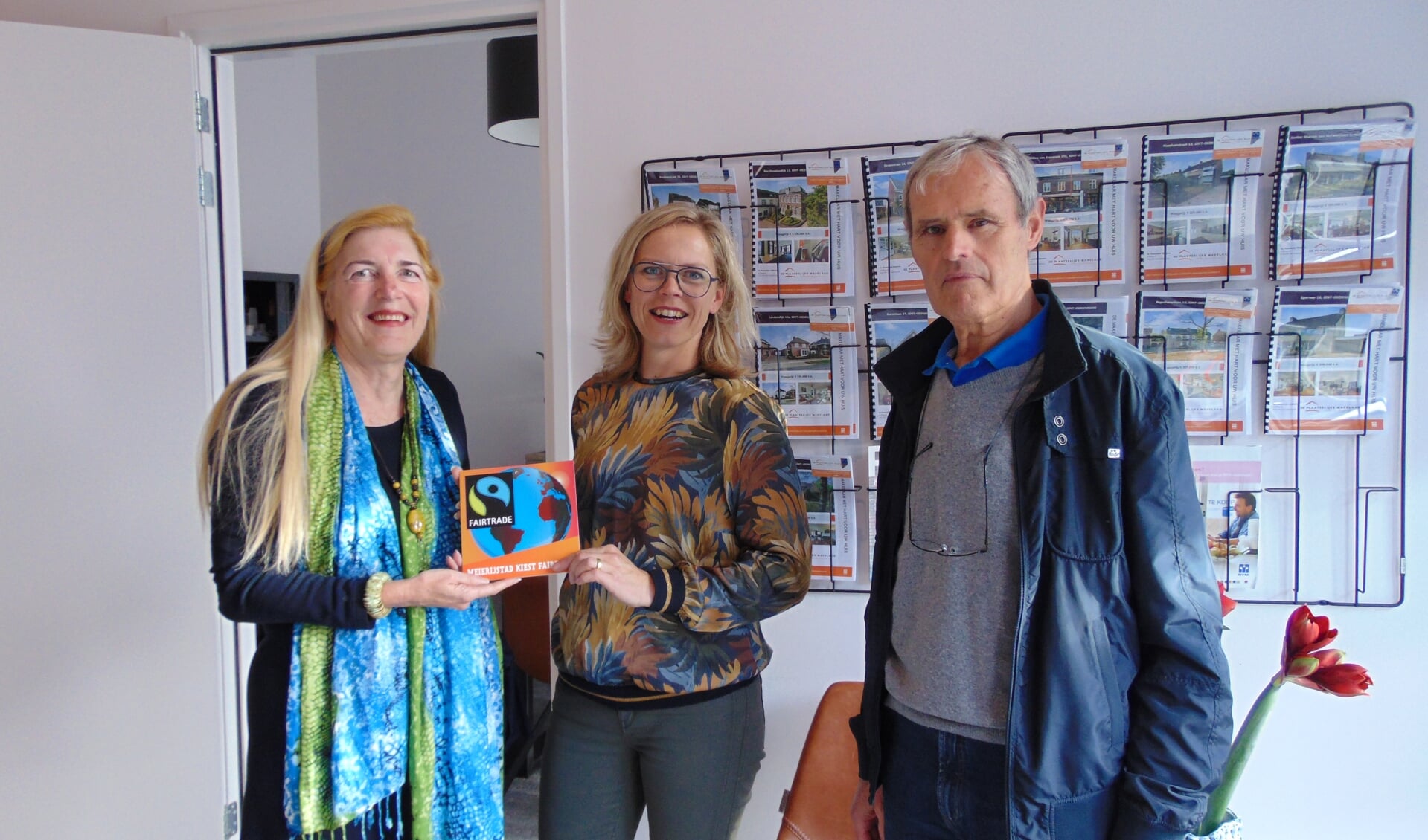 Marianne Bruin (links) en Piet van Berkel (rechts) van werkgroep Fairtrade Meierijstad reikten het vignet uit aan Carla van de Laar (midden) van De Plaatselijke Makelaar