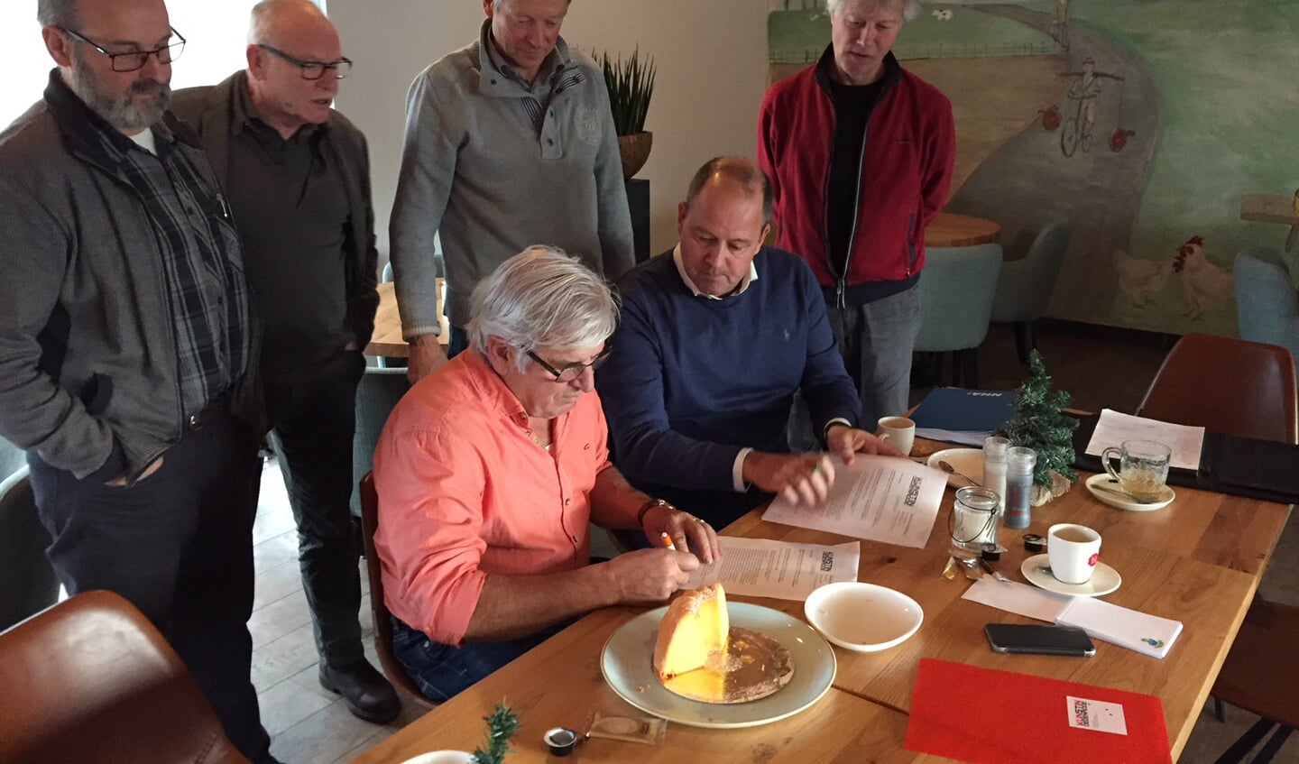 Joost van Dijk (voorzitter Kunststichting) en Piet Klaasen (voorzitter Oud-Rijsingen) tekenen de overeenkomst, de andere bestuursleden kijken kritisch toe.