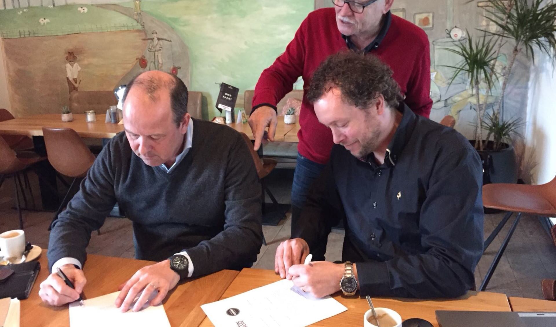 Joost van Dijk (voorzitter Kunststichting Sint-Oedenrode) en Rob Jansen (bestuurder Streekpark Kienehoef) tekenen de overeenkomst, de overige bestuursleden kijken toe.