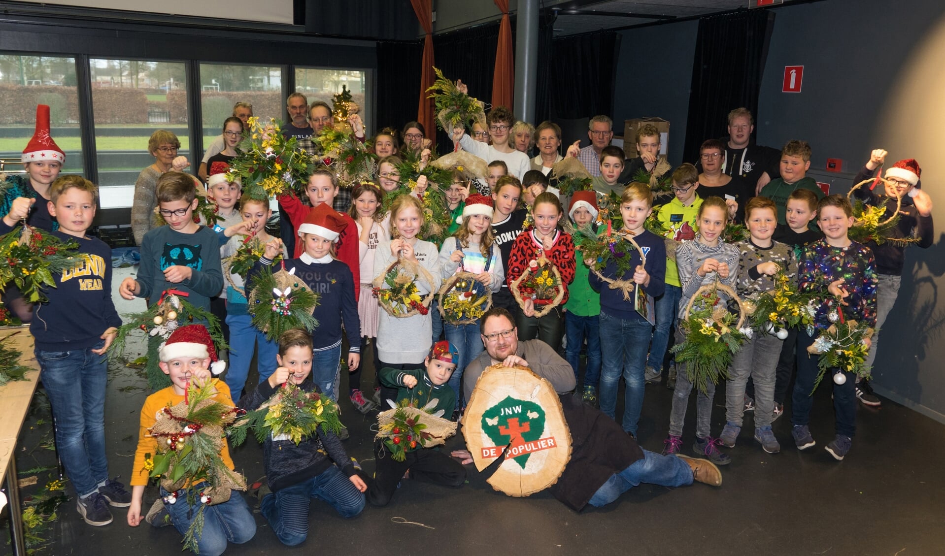 De jeugdnatuurwachters met hun eigengemaakte kerststuk samen met de leiding en wethouder Van der Pas.
