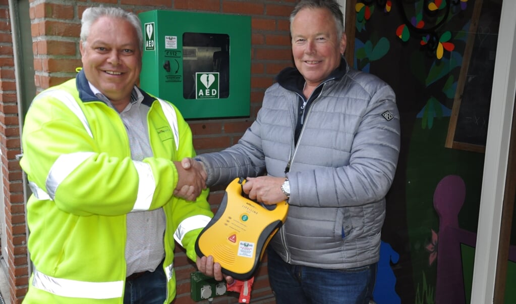 Marco Thijssen (l) levert het AED aan Ron van Rooij van Camping de Kienehoef.