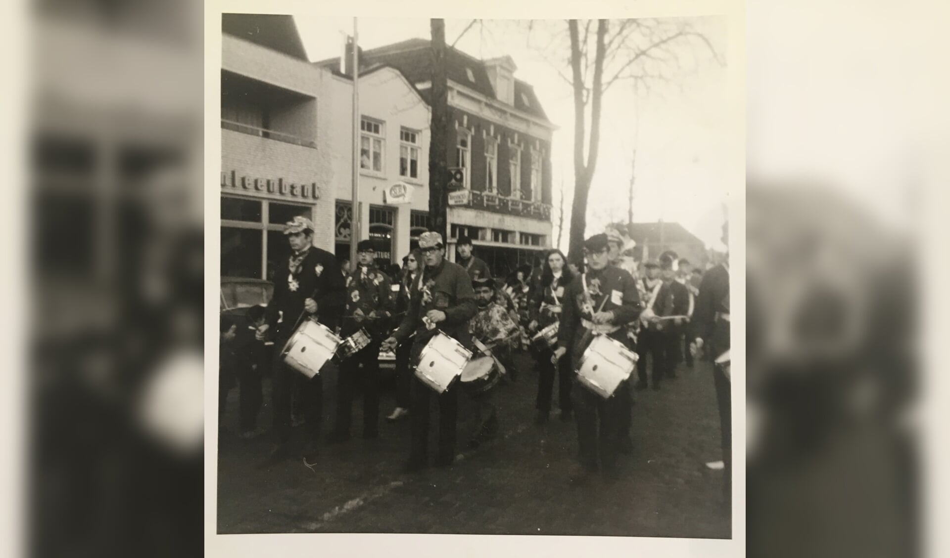 Harmonie Sint Antonius carnaval 1971. Vooraan: Jan Sijbers, Piet van de Sande, Wim van de Sande Gebouwen links: Boerenleenbank, Cafetaria Bert van de Akker, Muller mode