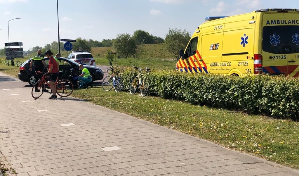 De fietser wordt door de ambulancemedewerkers geholpen.