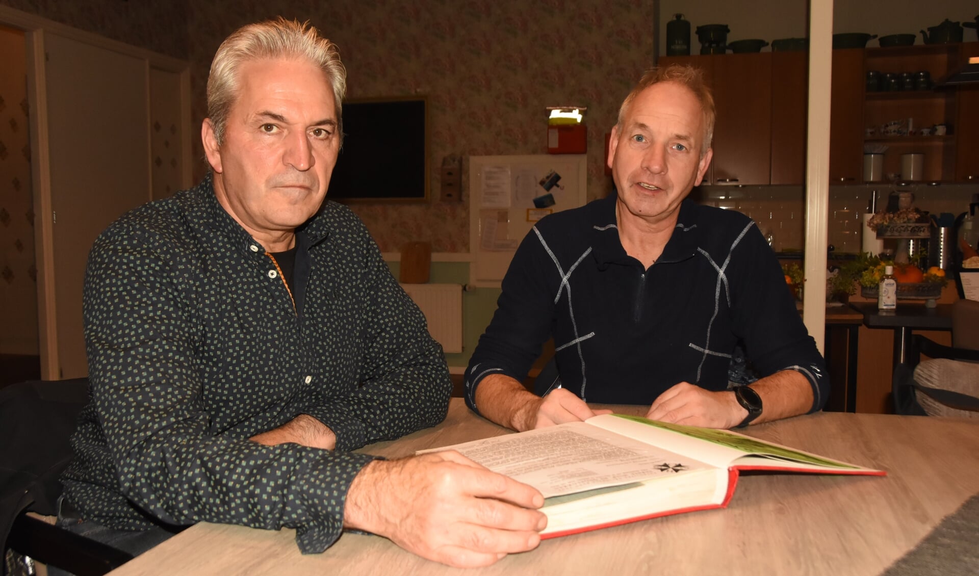 Wil van Vught en Piet van Rooij (r) bladeren door het archief van de bijna 85-jarige EHBO-vereniging
