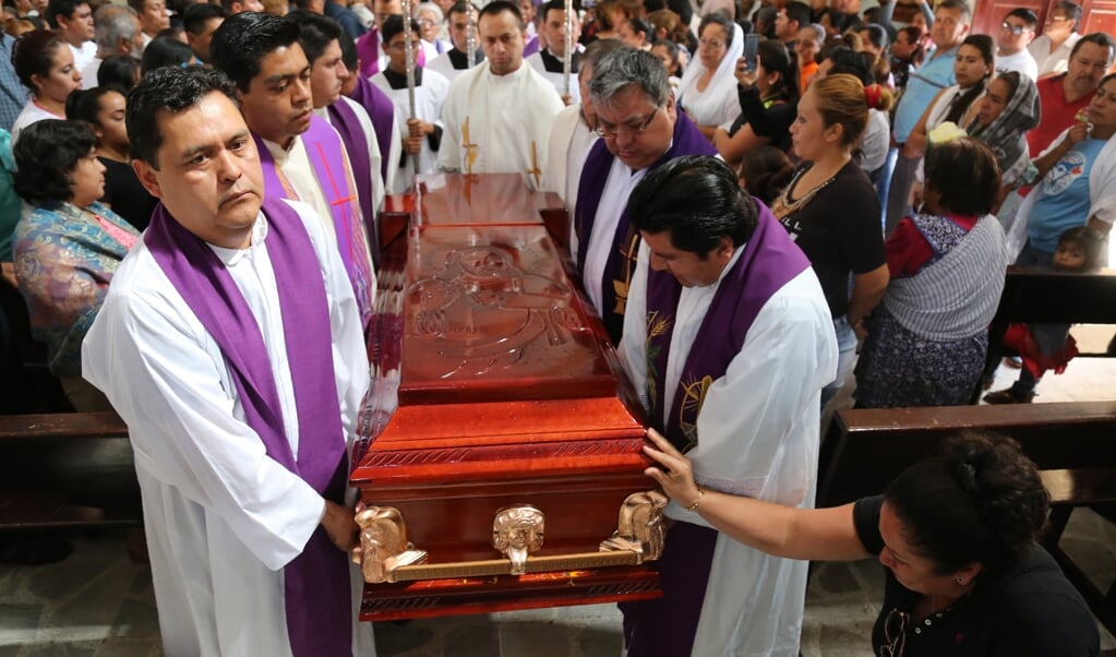Mexicaanse priesters begraven een andere priester die omkwam bij de aanval van een gewapende bende. Drugskartels vormen in het land een grote bedreiging voor kerkleiders. (beeld afp / Jesus Guerrero)