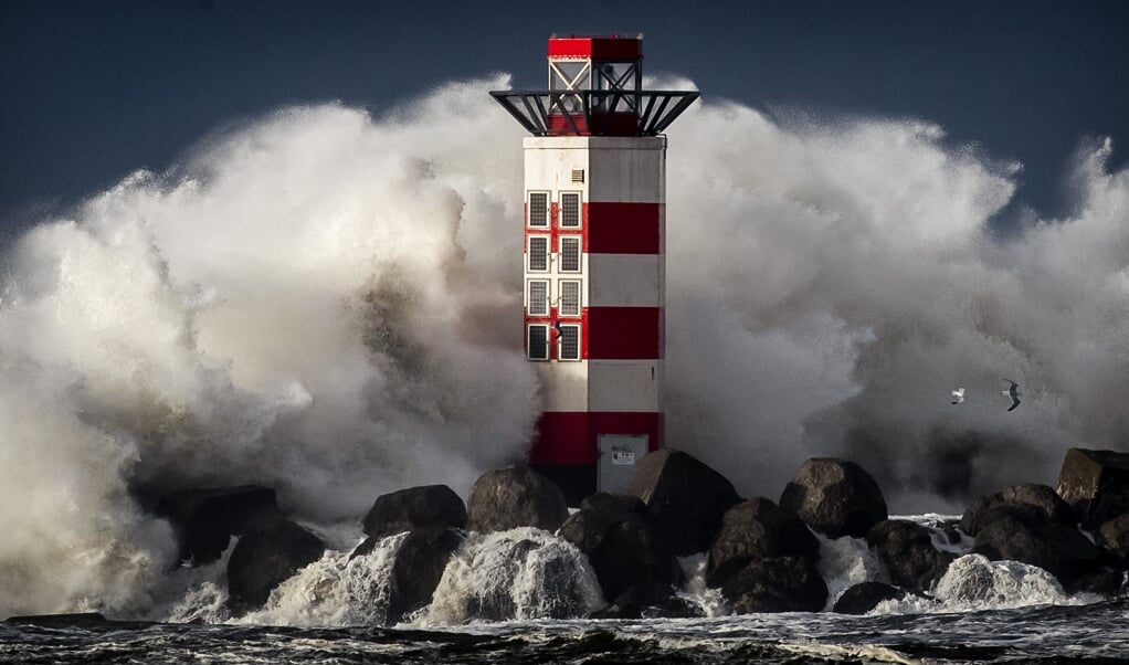 Grote golven slaan in IJmuiden tegen het baken op de kop van de pier tijdens stormachtig weer. Wetenschappers hebben plannen gemaakt om de Noordzee in te dammen in de strijd tegen een hogere zeespiegel. (beeld anp / Koen van Weel)
